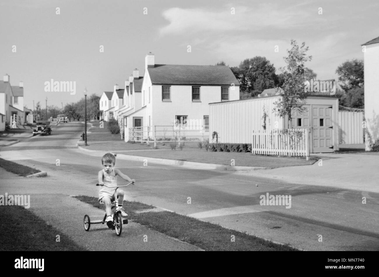 Young Boy Riding Tricycle, Greendale, Wisconsin, USA, a Greenbelt Community Constructed by U.S. Department of Agriculture as Part of President Franklin Roosevelt's New Deal, John Vachon for U.S. Resettlement Administration, September 1939 Stock Photo