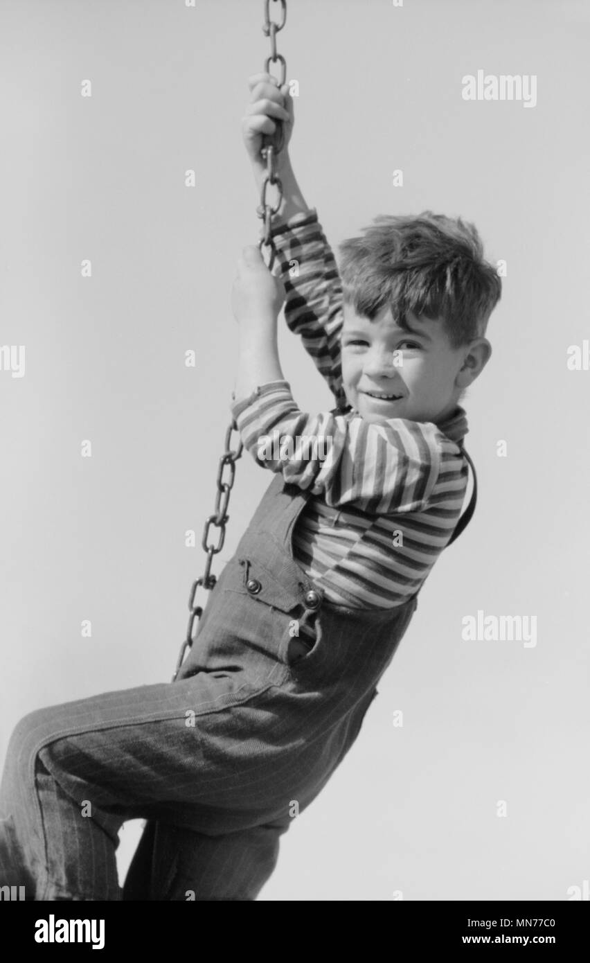 Portrait of Young Boy Hanging on Swing Chain at Playground, Child of Migratory Worker, Weslaco, Texas, USA, Arthur Rothstein for Farm Security Administration, January 1942 Stock Photo