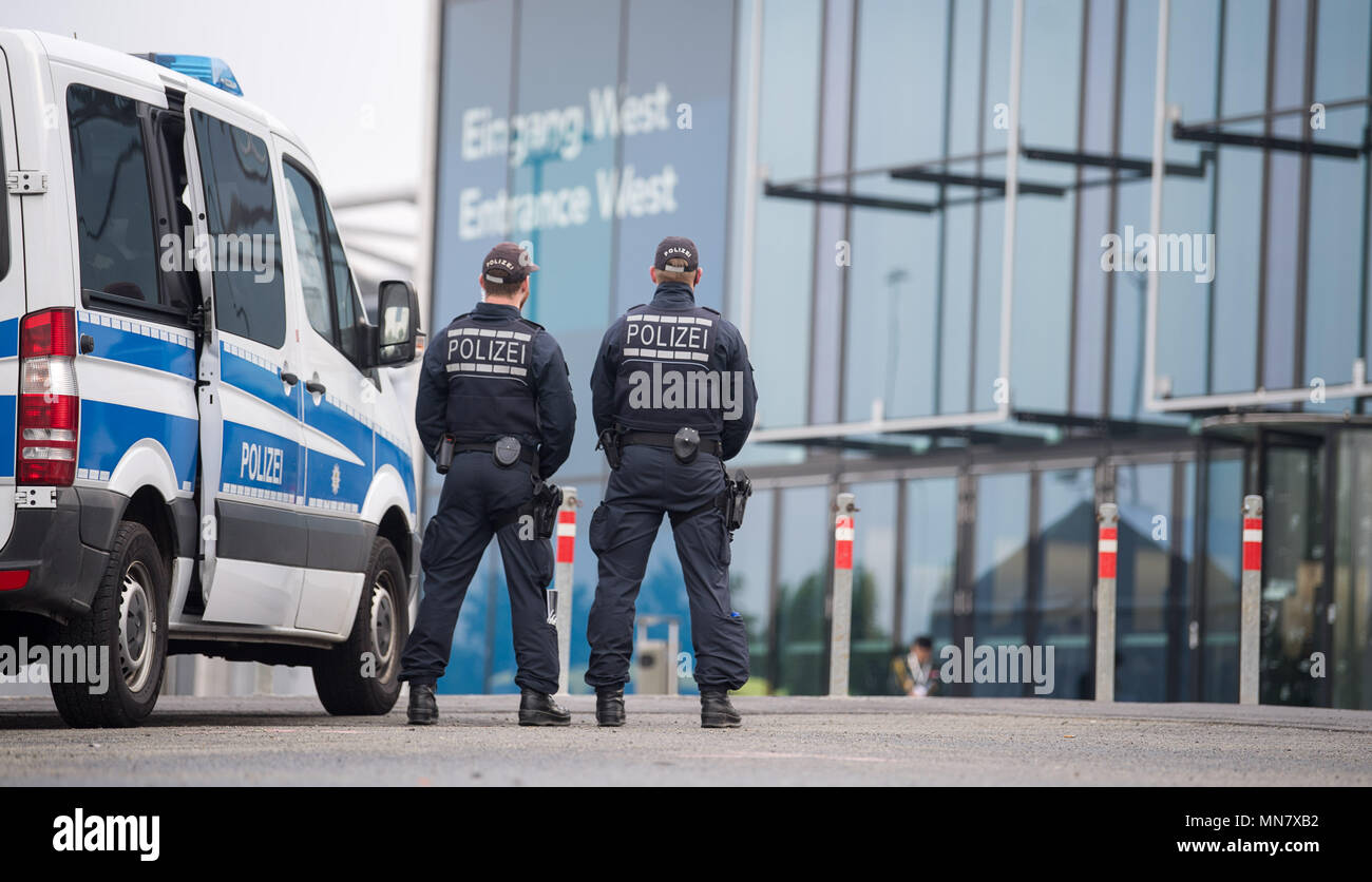 Stuttgart, Germany. 15th May, 2018. 15 May 2018, Germany, Stuttgart: Police officers guard the entrance of the fair on the first day of the ITEC fair for military and weapons technology. The fair, which presents training and simulation software, among others, is running from 15 to 17 May. It is accompanied by demonstrations by opponents of weaponry. Photo: Sebastian Gollnow/dpa Credit: dpa picture alliance/Alamy Live News Stock Photo