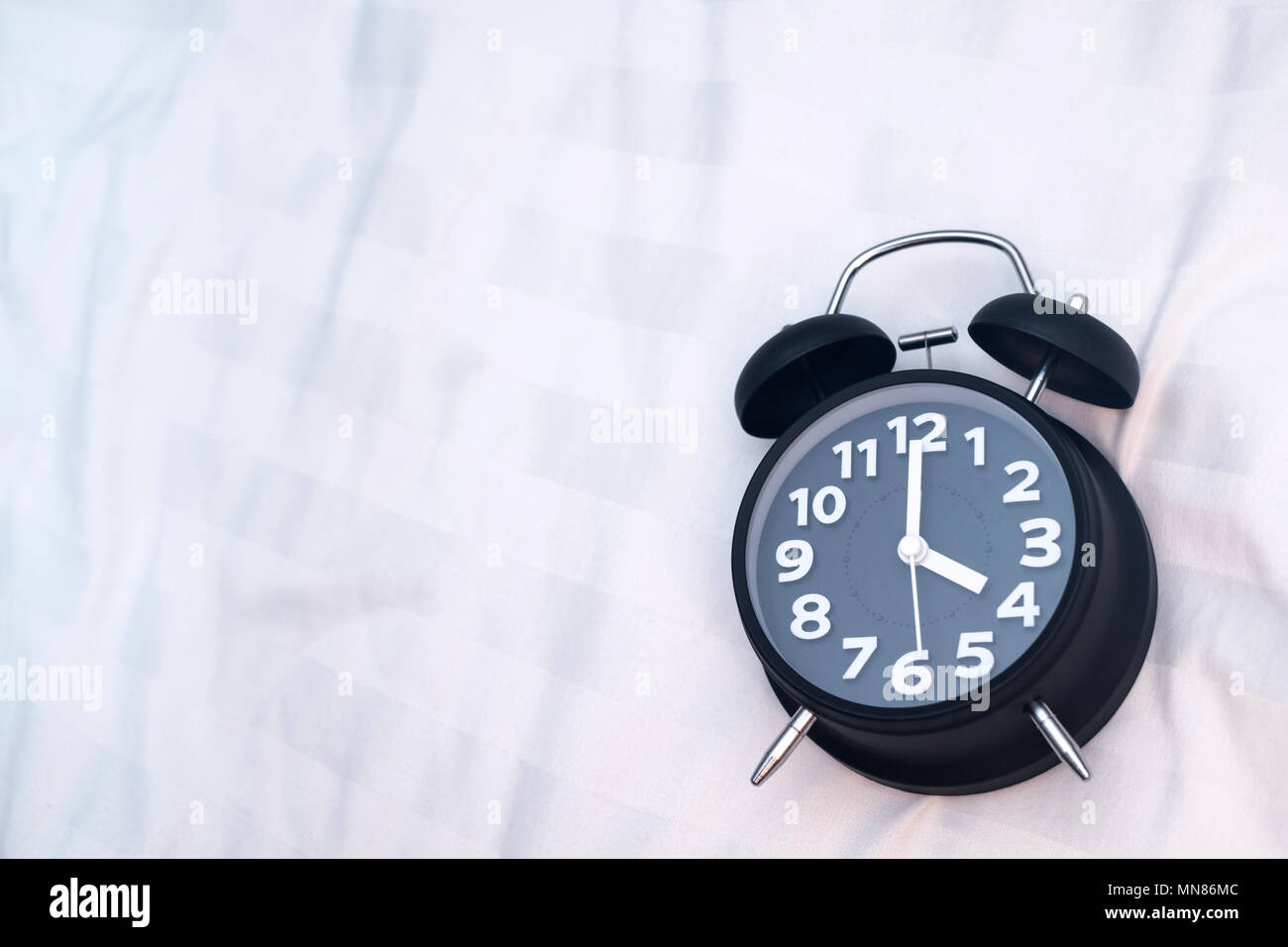 Vintage alarm clock on the bed in bedroom at home, wake up or bed time