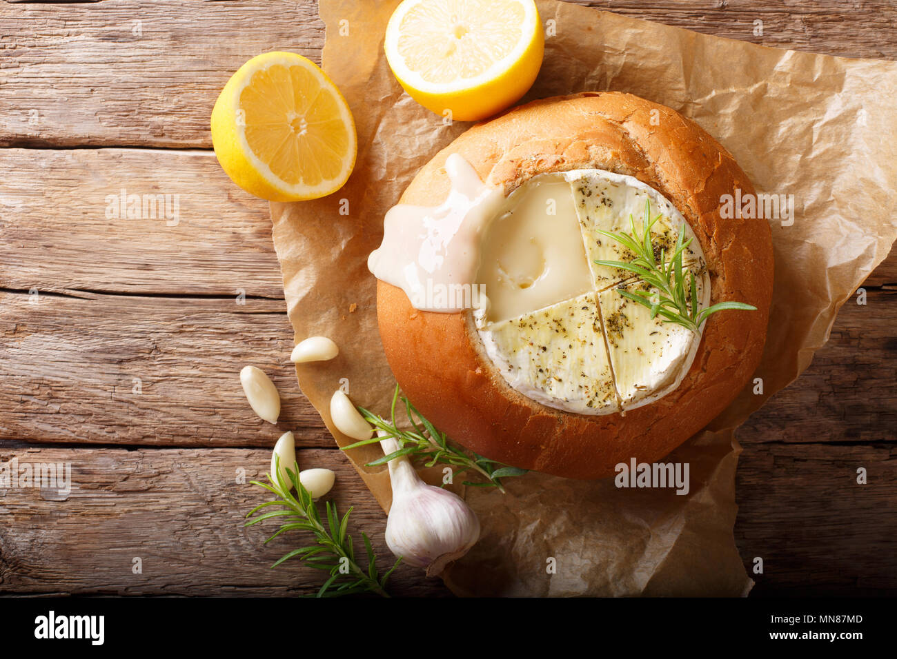 Fondue in a loaf of bread from melted camembert cheese closeup on a table. horizontal top view