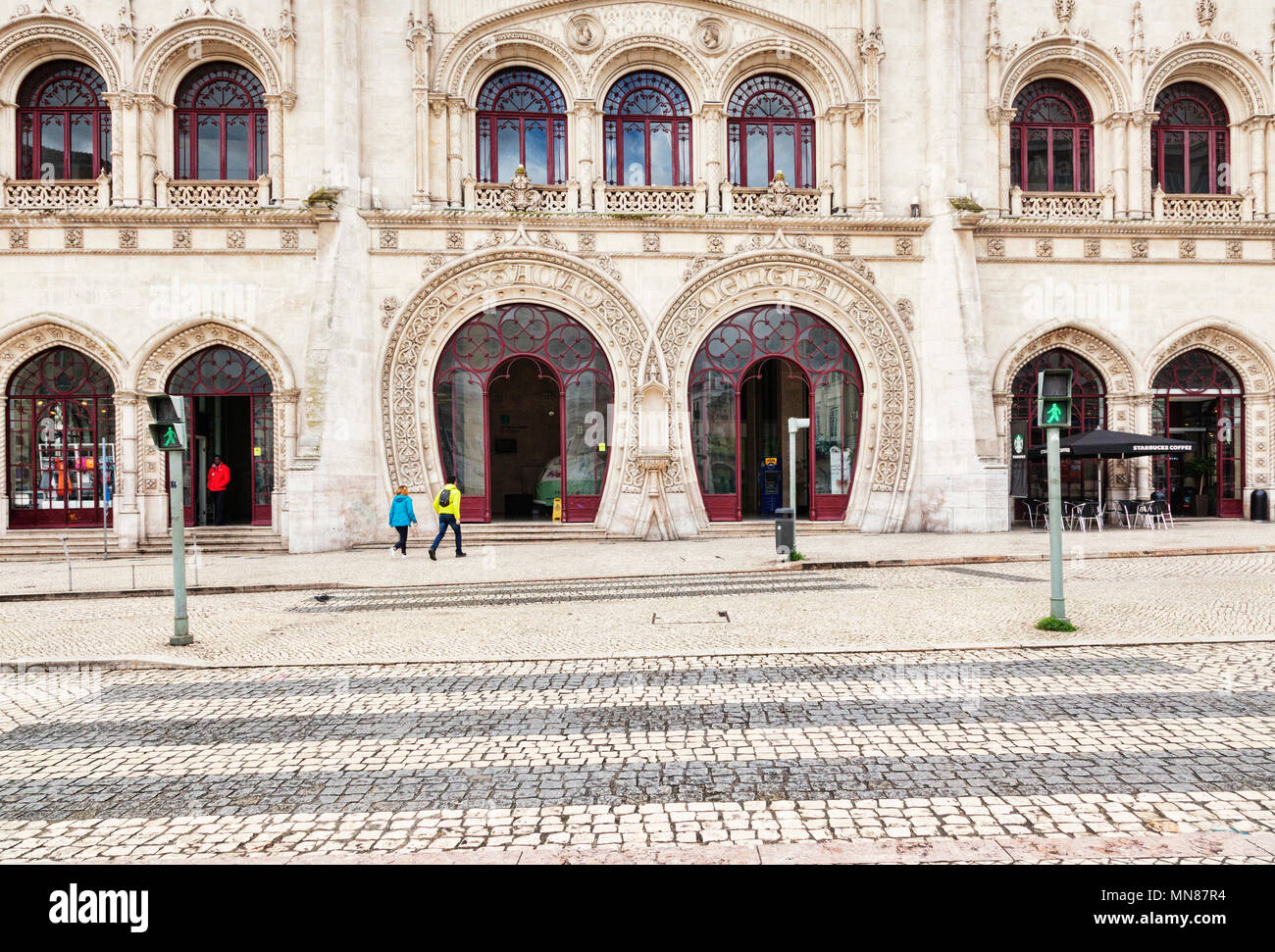 3 March 2018: Lisbon, Portugal - the arched facade of Rossio Railway Station, a couple making their way to the entrance. In the foreground a pelican c Stock Photo