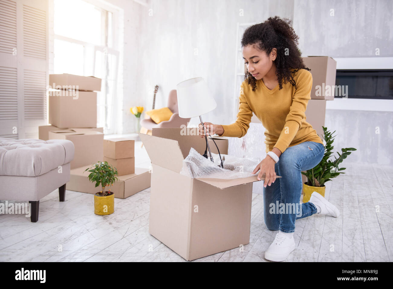 Pleasant young girl packing lamp into the box Stock Photo
