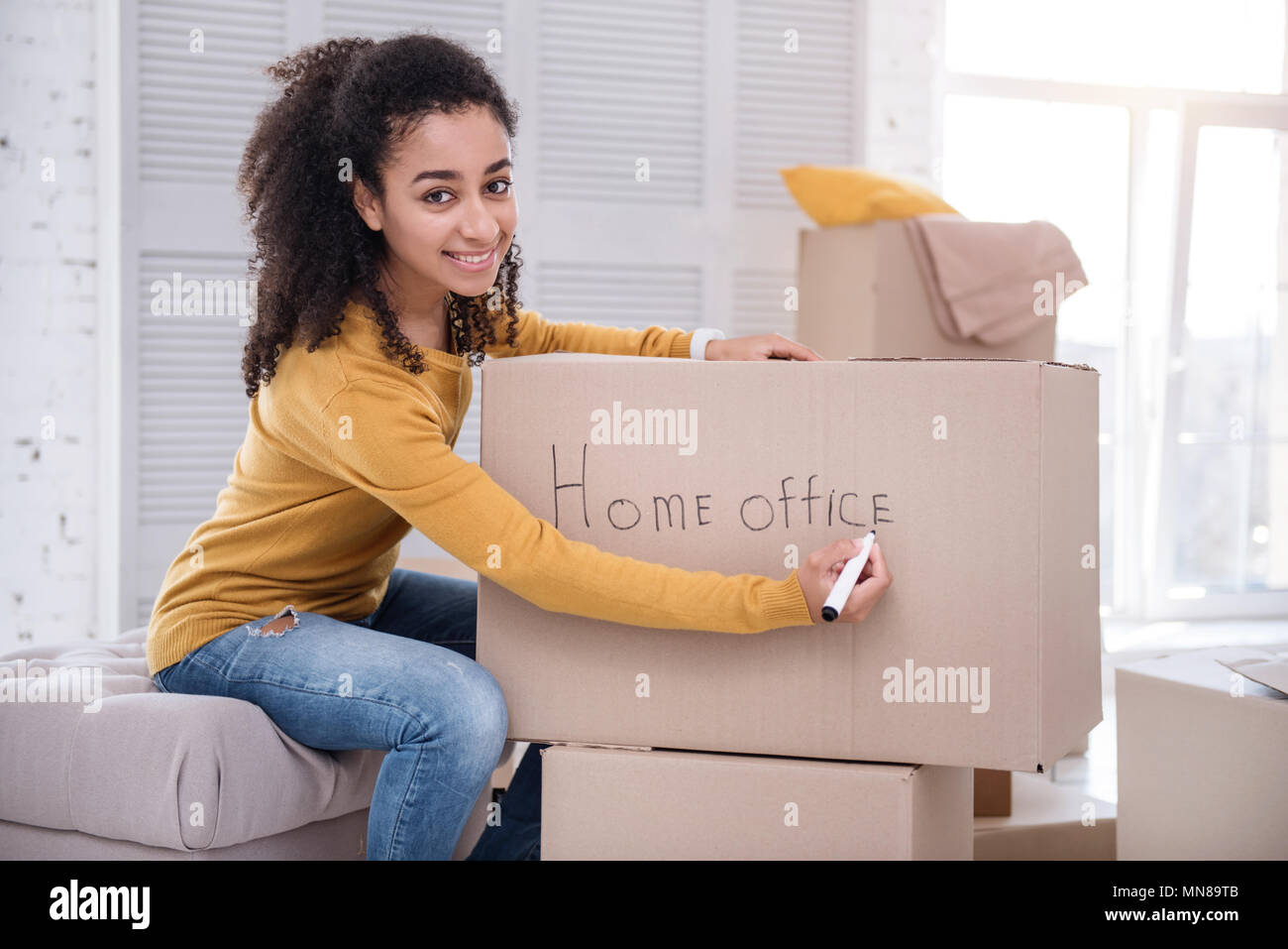 Upbeat girl signing box with belongings for home office Stock Photo