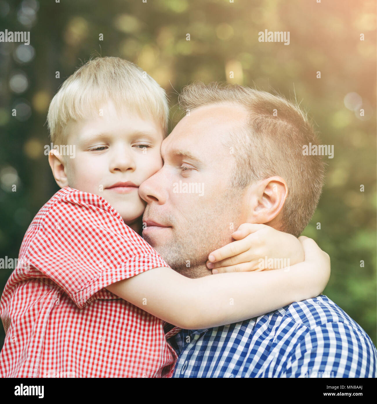 Father and little son hugging and smiling in the garden. Masculinity concept. Stock Photo