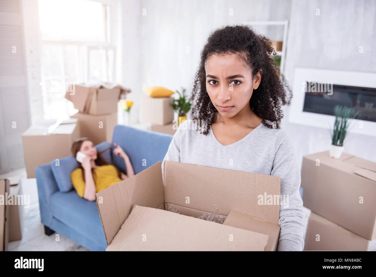Curly girl being annoyed receiving no help from roommate Stock Photo