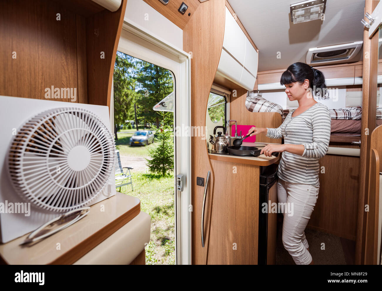 Woman cooking in camper, motorhome RV interior. Family vacation travel, holiday trip in motorhome, Caravan car Vacation. Stock Photo