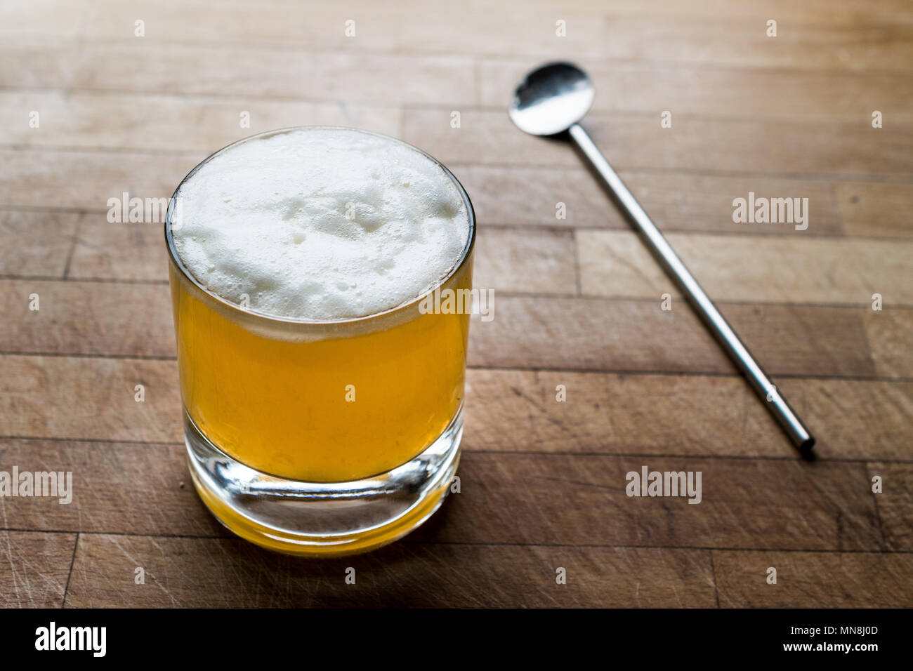 Whiskey sour cocktail with foam on wooden surface. Beverage concept