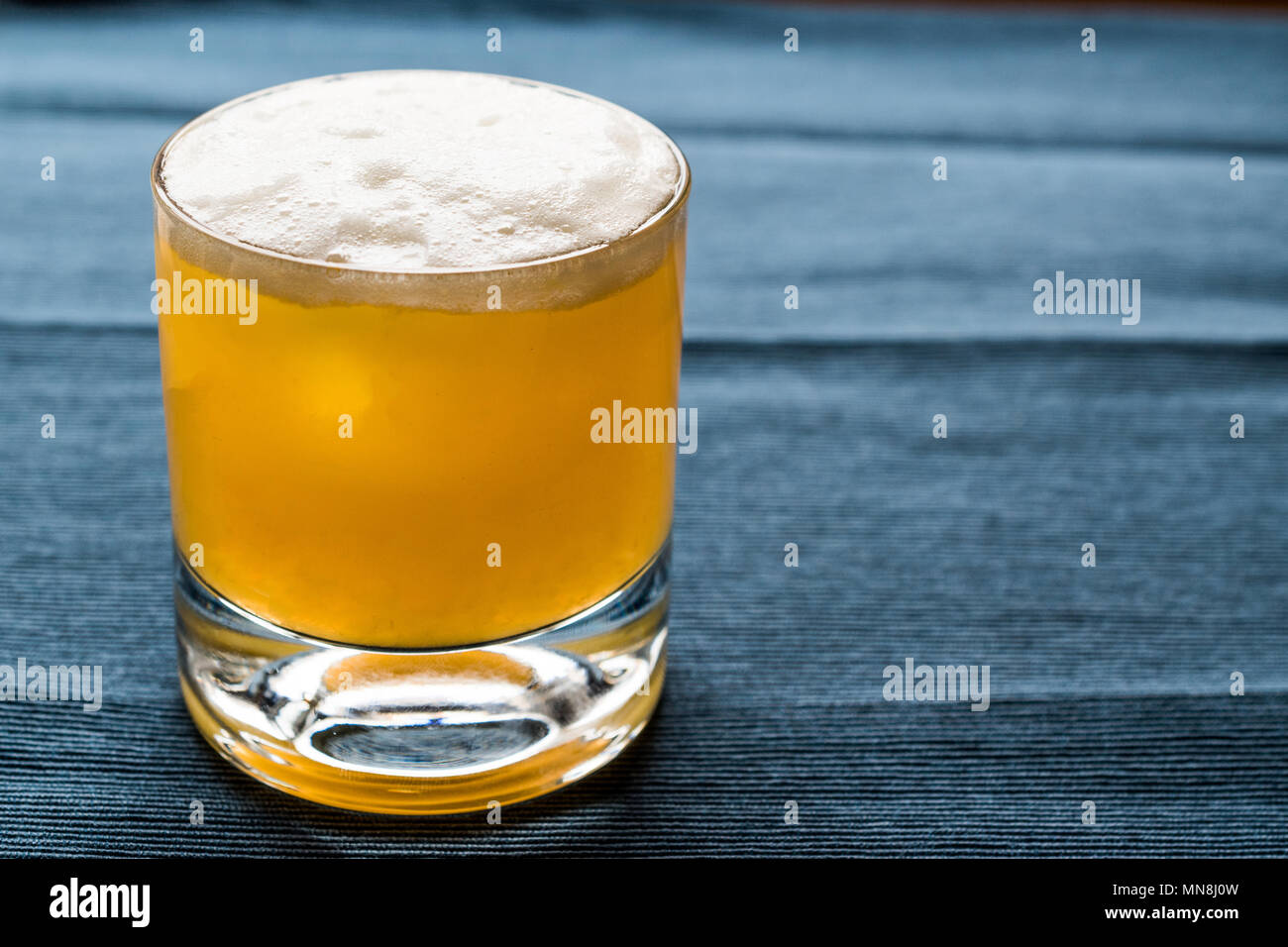 Whiskey Sour Cocktail with foam and blue backround. Beverage concept