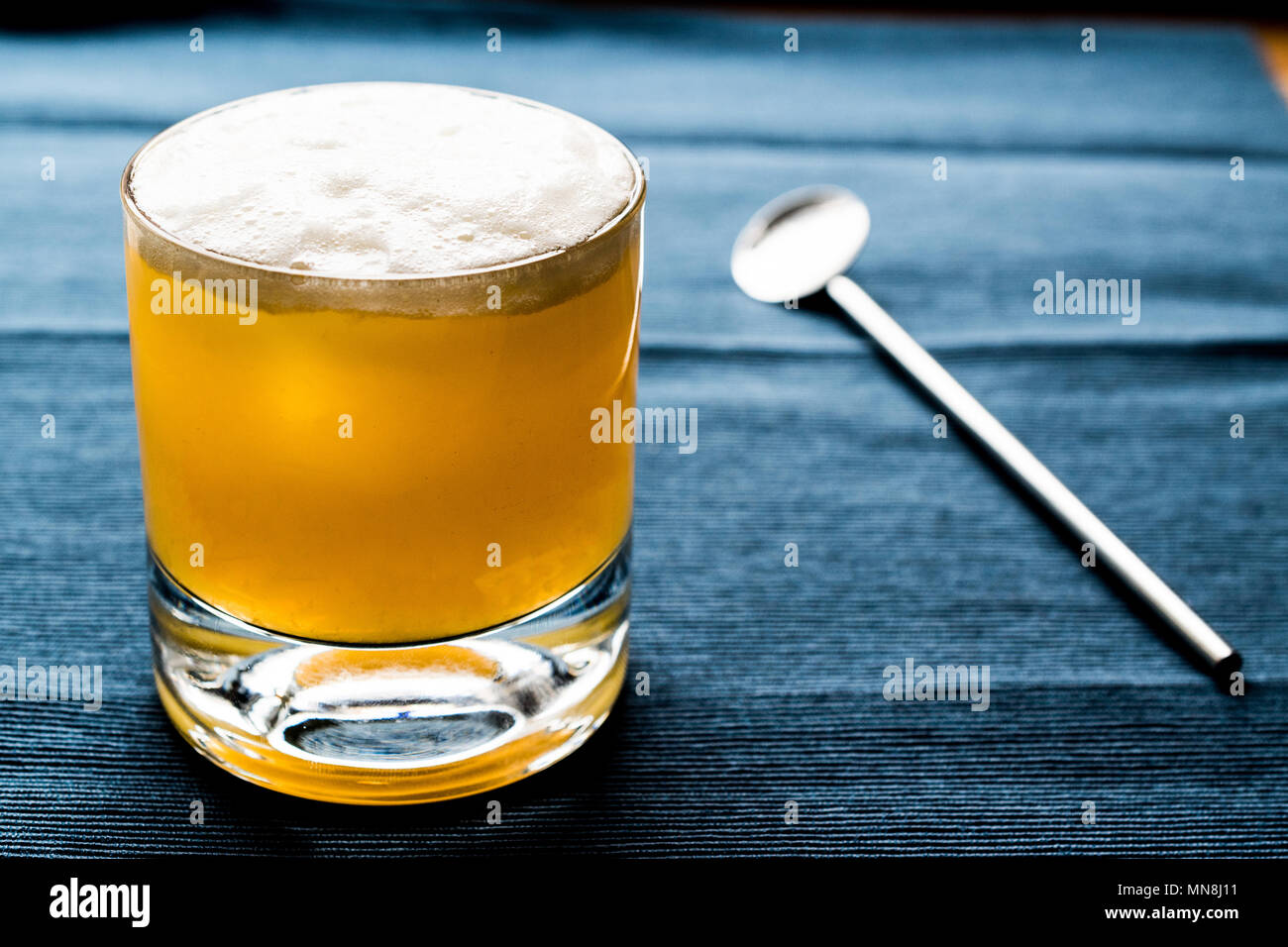 Whiskey Sour Cocktail with foam and blue backround. Beverage concept