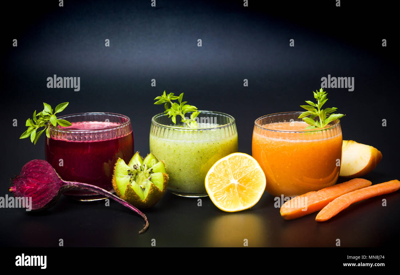 Kiwi beet and carrot smoothies in glasses on dark background Stock Photo