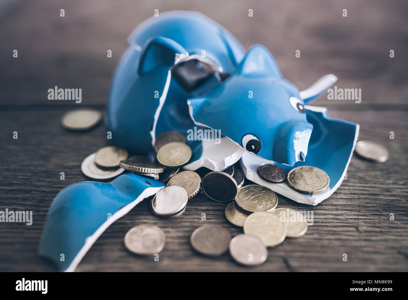 shattered broken piggy bank with coins on rustic wooden table Stock Photo