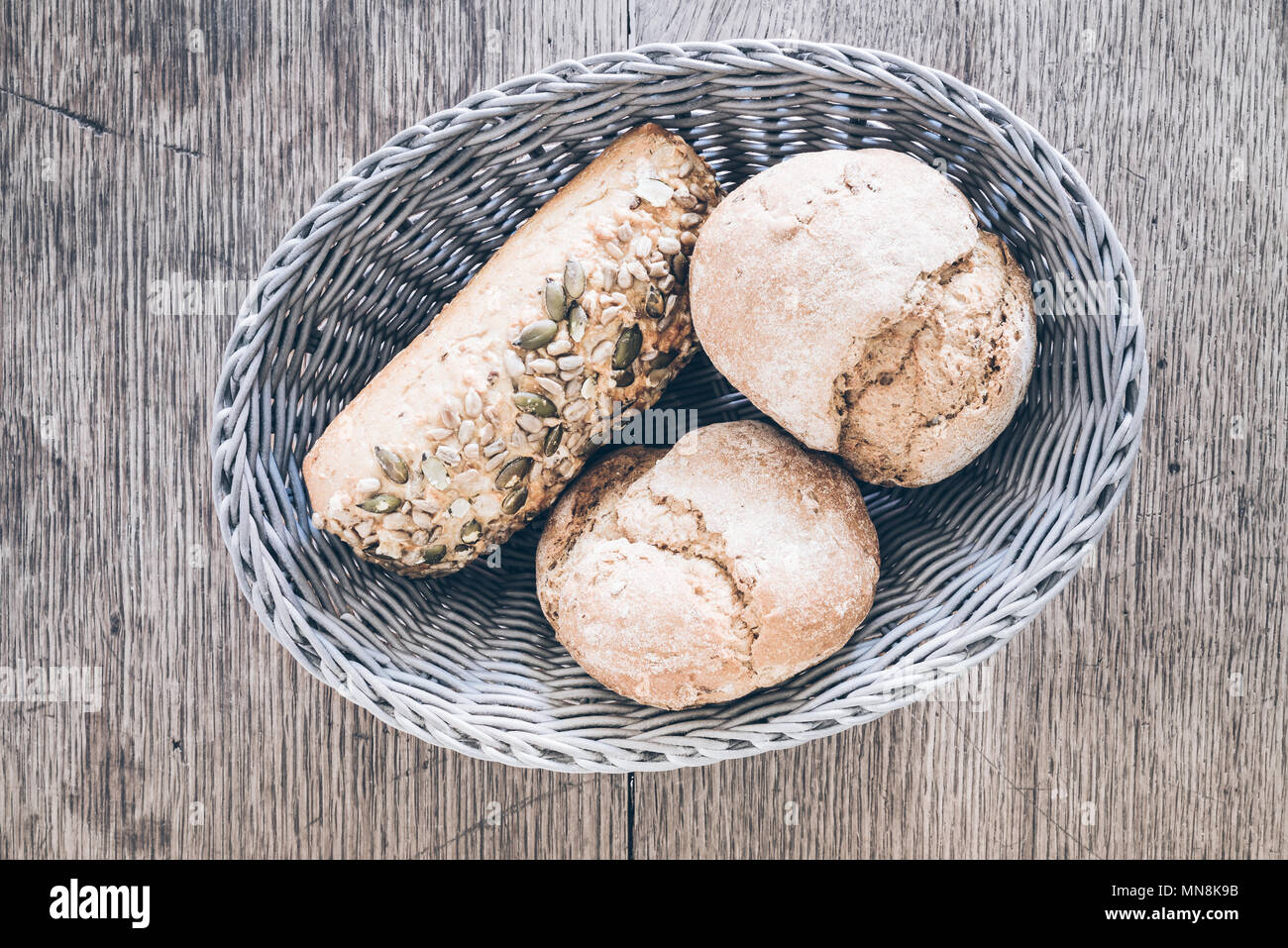 top view of basket with German style bread rolls on rustic wooden table Stock Photo
