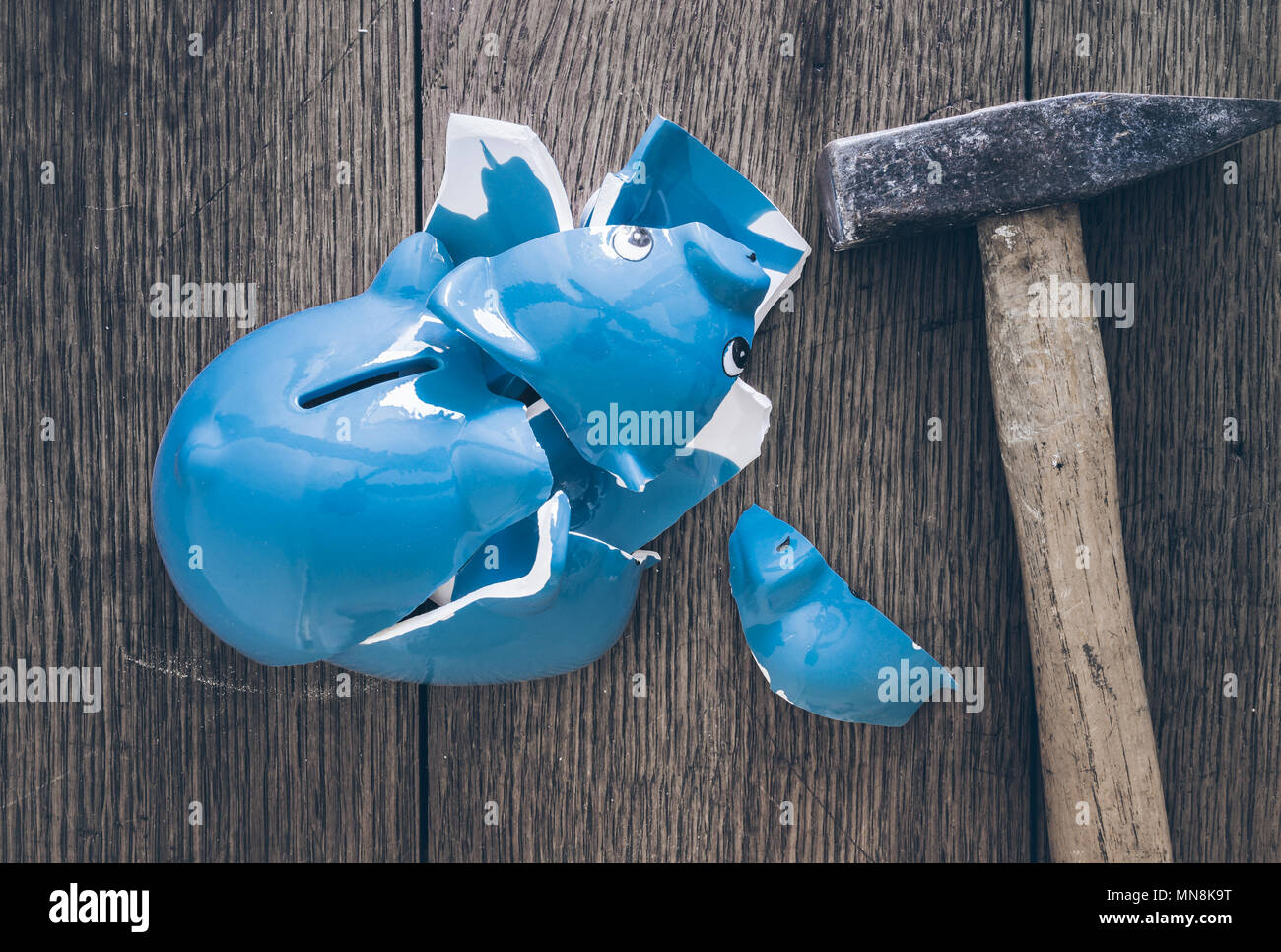 top view of shattered piggy bank and hammer on rustic wooden table Stock Photo