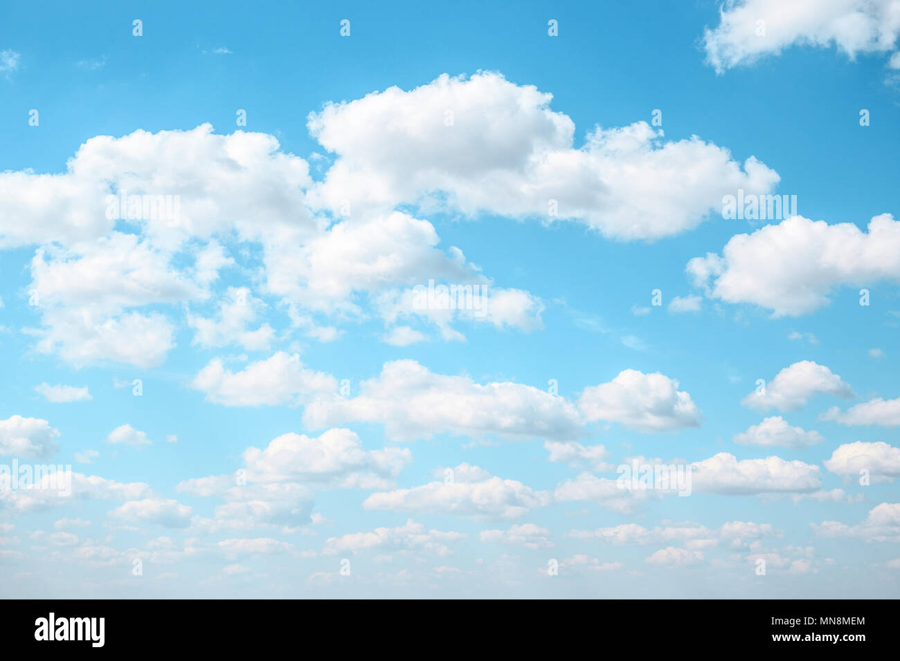 White Fluffy clouds in the light blue sky. Gradient Celestial Azure background. Cloudscape in sunny summer day. Stock Photo