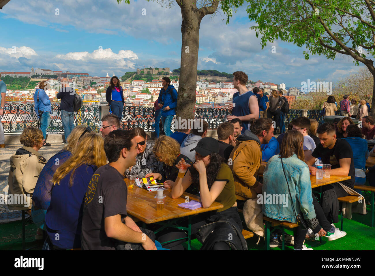 Lisbon young people, view of young people sitting on a terrace in the Miradouro de Sao Pedro de Alcantara with a view of Lisbon castle in the distance. Stock Photo