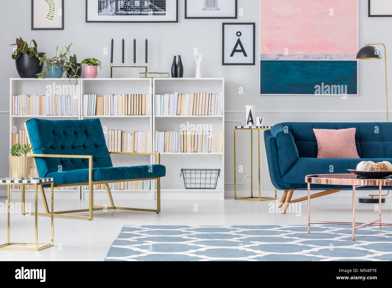 Navy blue armchair against bookshelf in living room interior with couch