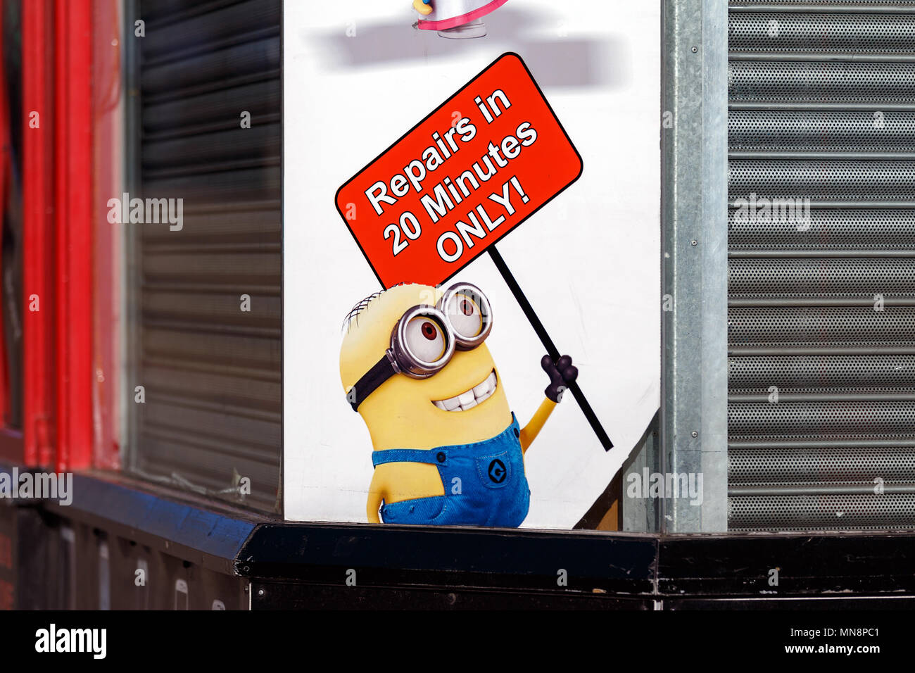 A minion, from the movie franchise Despicable Me and later Minions, being used to advertise a closed phone repair shop. Stock Photo