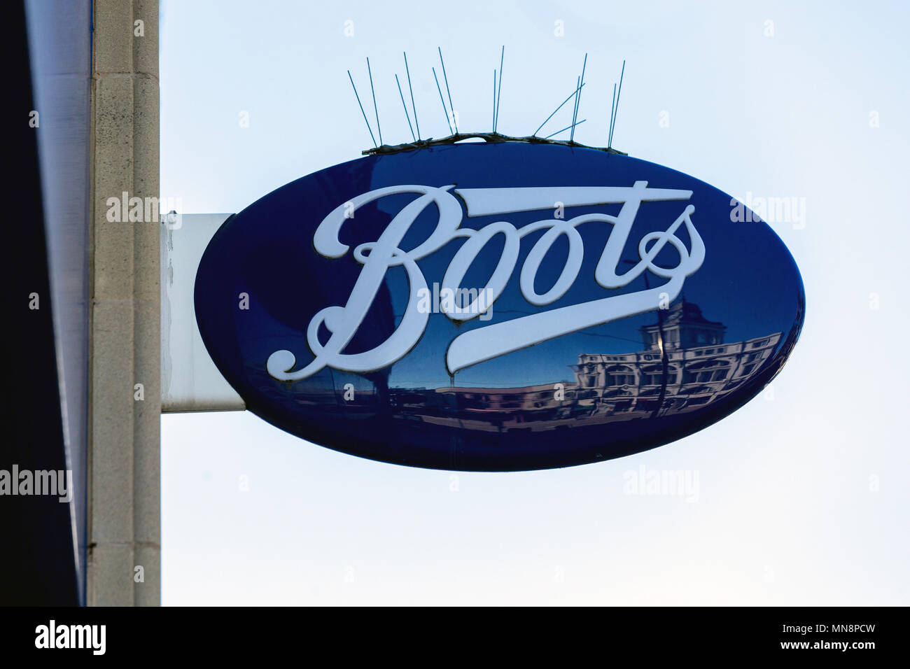 The signpost for a branch of Boots in the United Kingdom, pictured in 2018. Spikes designed to deter birds from perching are placed on top. Stock Photo