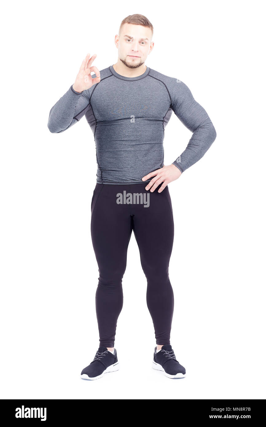 Portrait of handsome well-muscled gym instructor in sports tights and rashguard posing on white background Stock Photo