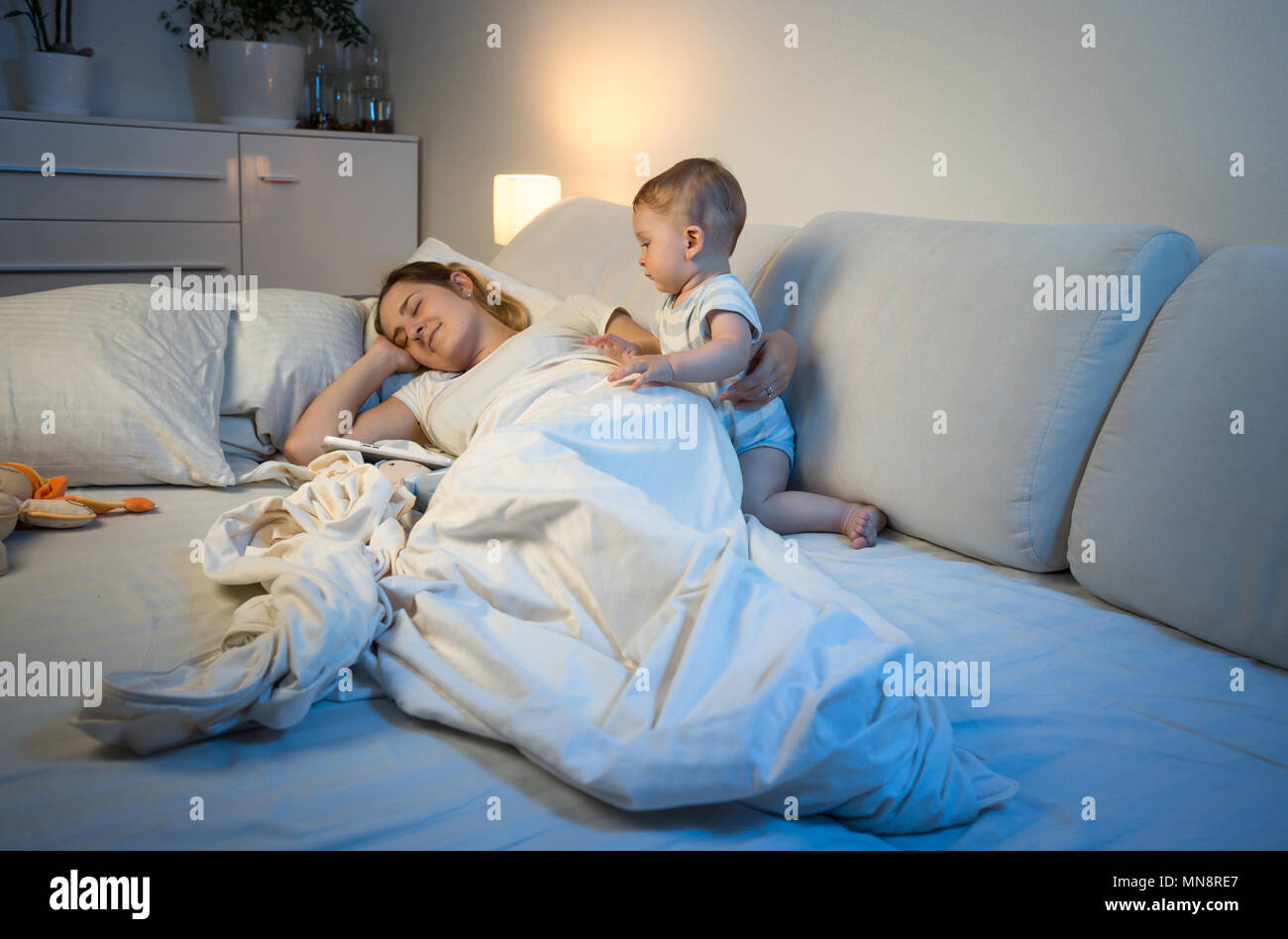 Young mother fell asleep next to her baby boy in bed Stock Photo
