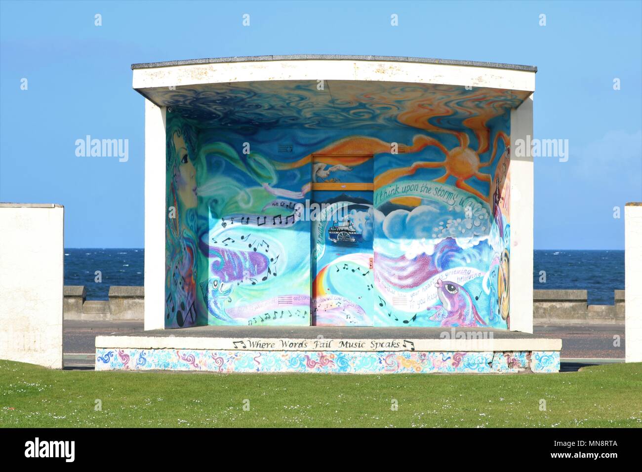Shelter painted with art on seafront with sea in background against a blue sky at Ayr, Scotland, UK. Stock Photo