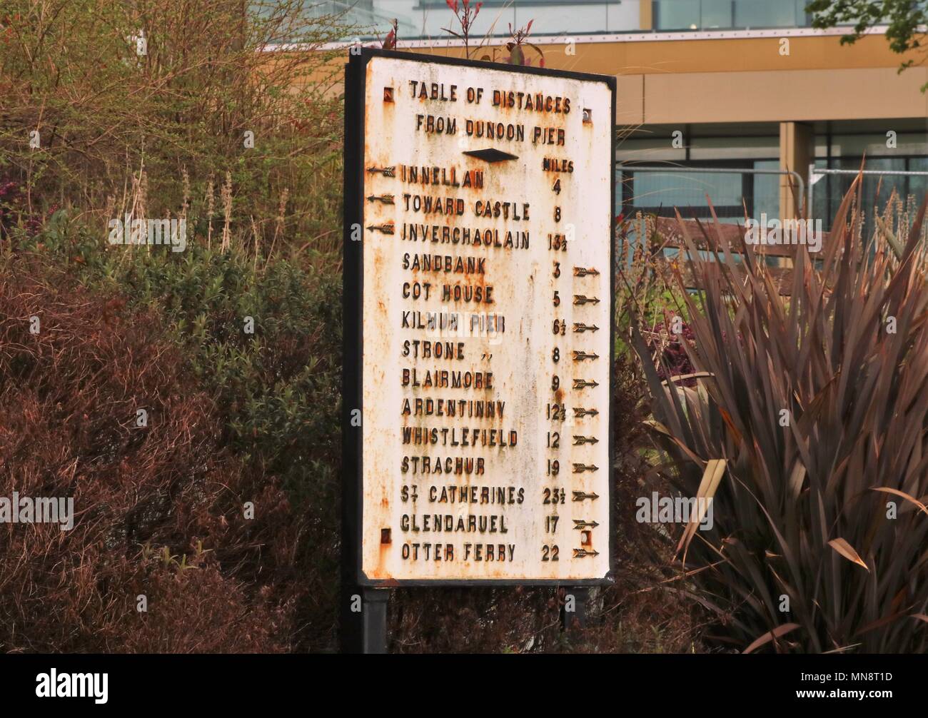 Old and weathered sign showing 'Table of Distances from Dunoon Pier' in miles at the side of the road at the entrance to Dunoon Pier, Scotland, UK Stock Photo