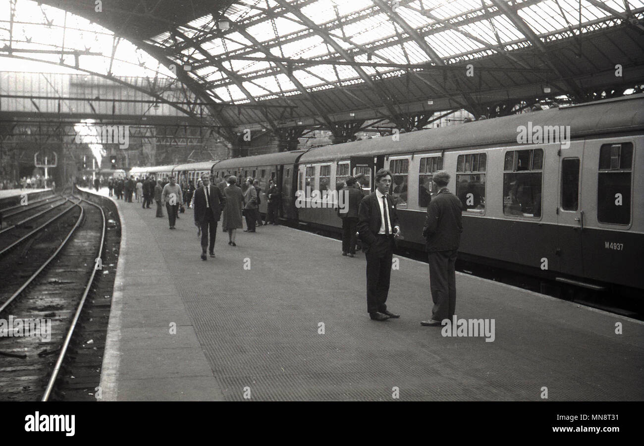 1960s, historical picture of Liverpool lime street railway station, showing passengers on the platform about to aboard a train carriages. This was still the era of steam locomotives as can be seen in the distance. Stock Photo