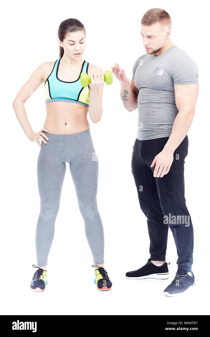 Gym trainer assisting fit young woman doing dumbbell exercise Stock ...