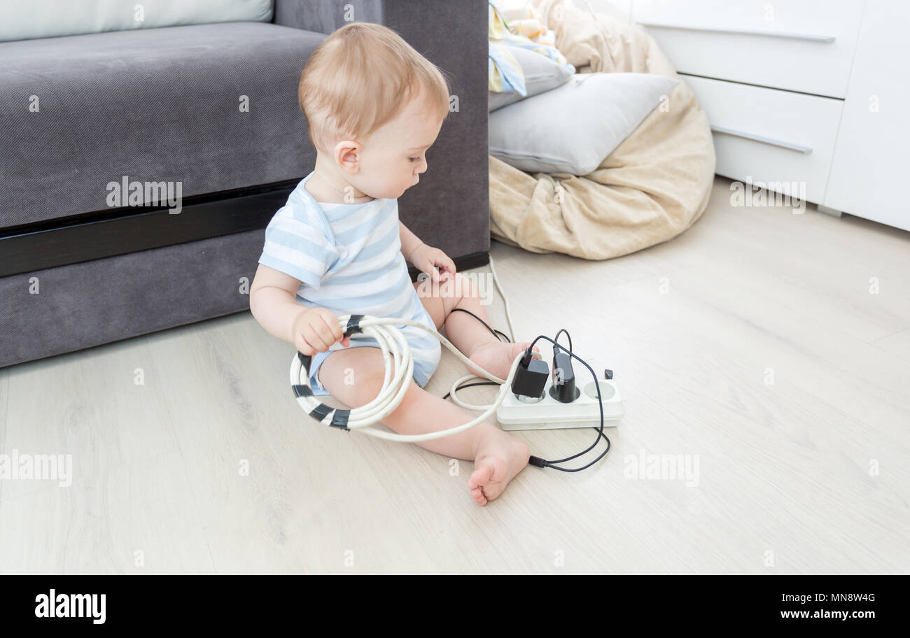 Unatteded little baby boy playing with electric power cables. Child in dangerous situation Stock Photo