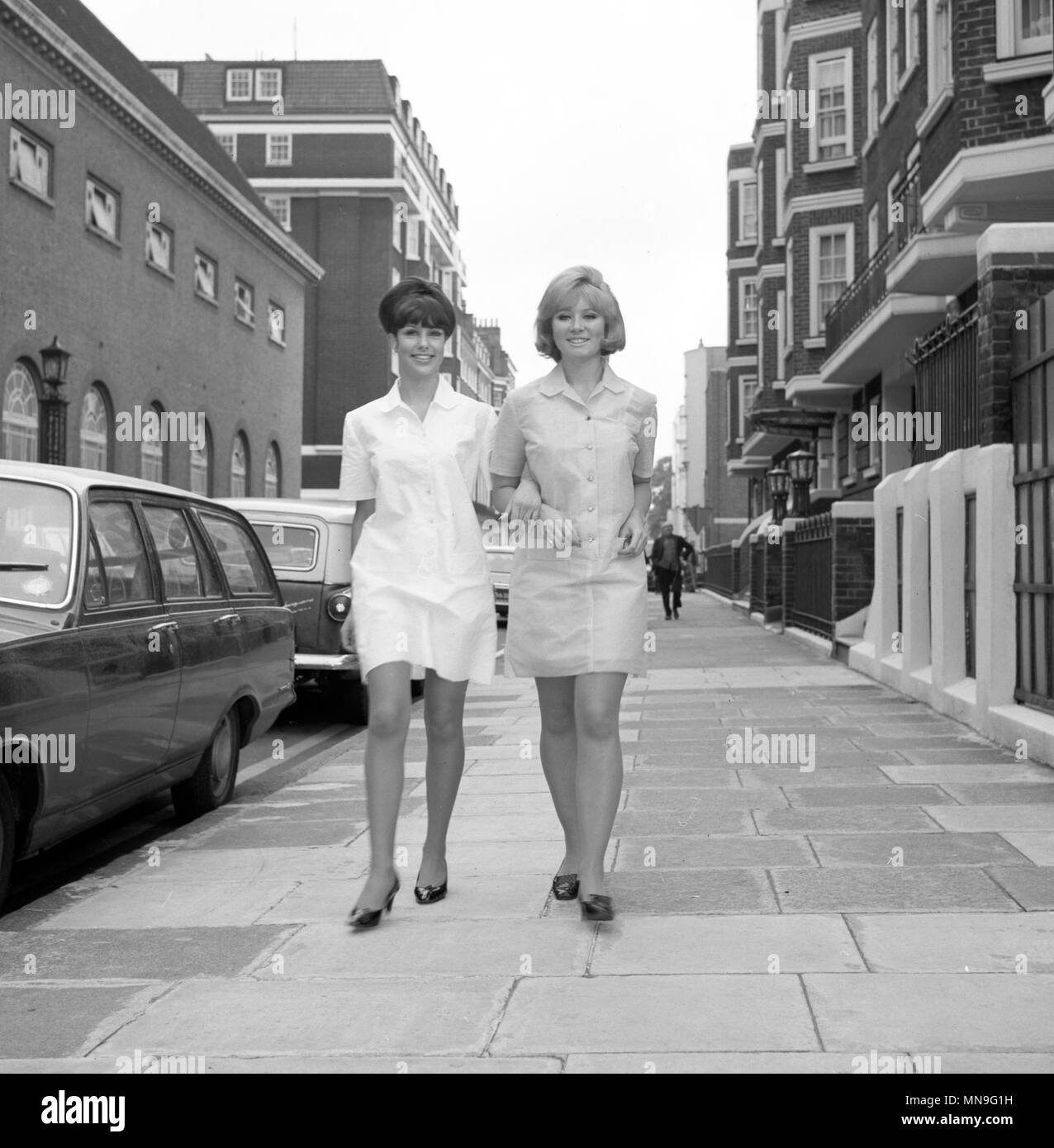 Janet Gale (l) and Christine Pryor, in London, wearing revolutionary national style disposable dresses which are a designed by E & R Garrould Ltd, of London. The girls are on their way to the company's stand at the London Nursing Exhibition, which opens at the Seymour Hall, London. The dresses are made of disposable fabric, with the uniform designed to the recommended style of the National Health Service work group, whose report was published recently. Stock Photo