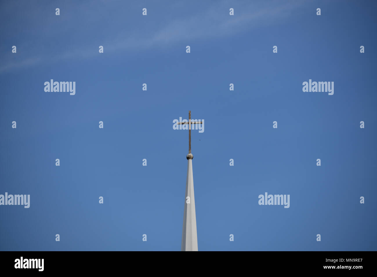 'The Steeple' American Series' a cross sits high atop a traditional church steeple against the backdrop of a clear blue sky Stock Photo