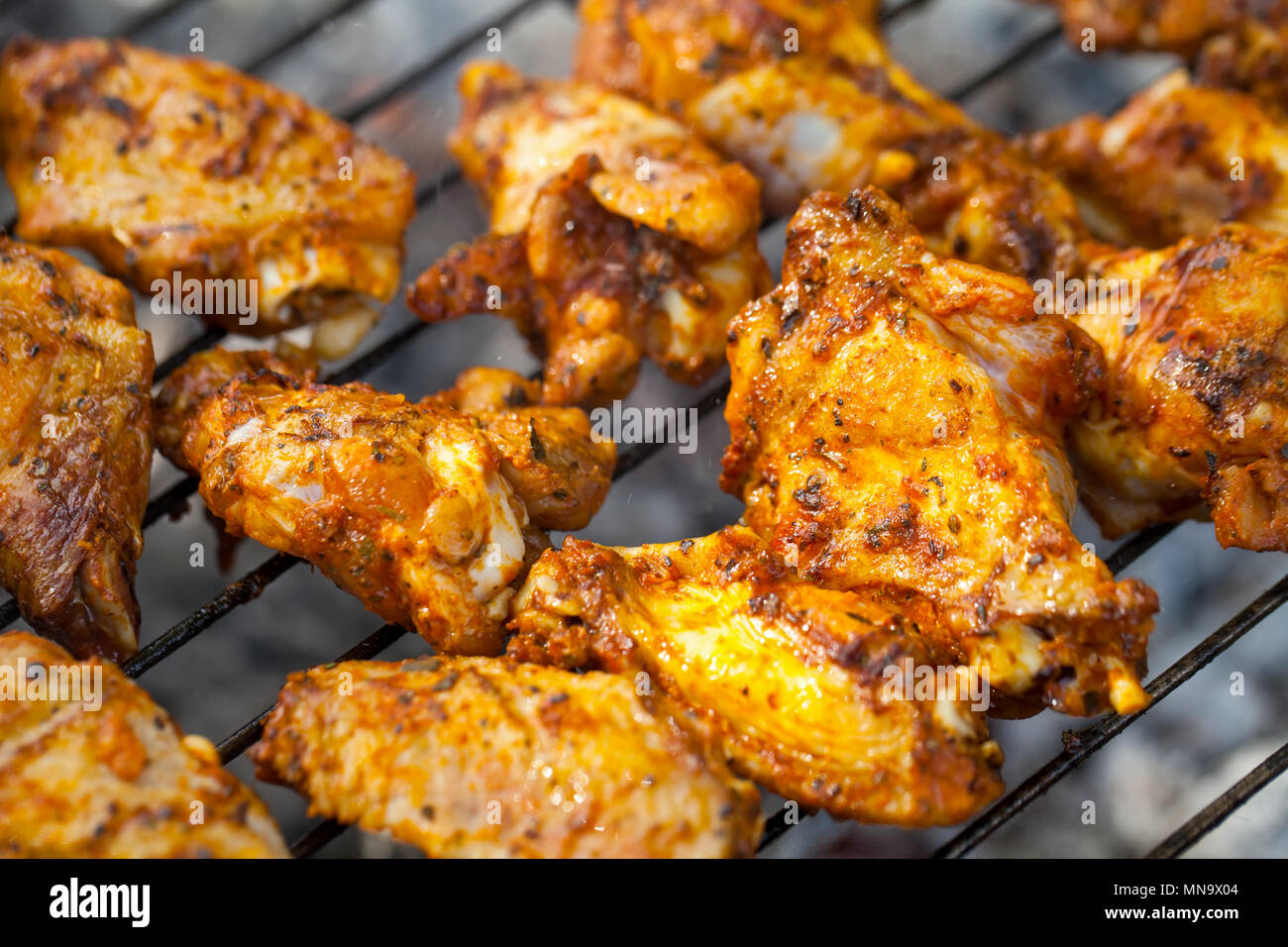 Close up picture of marinated chicken wings grilled over fire on a
