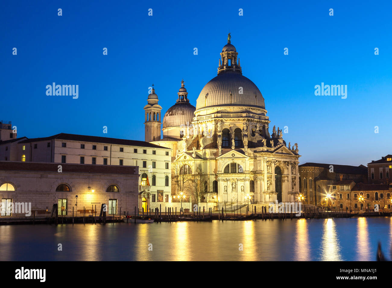 Basilica di Santa Maria della Salute illuminated at blue hour, twilight, dusk, Grand Canal, Dorsoduro, Venice, Veneto, Italy. Long exposure with refle Stock Photo
