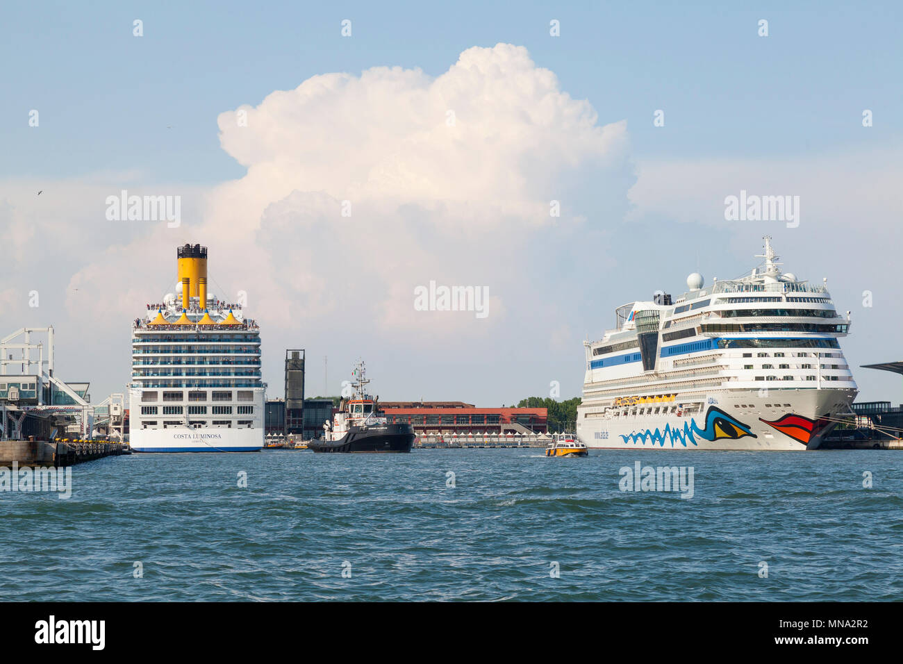 The Costa Luminosa and Aidablu cruise liners in port, Venice, Veneto, Italy with a tug standing by to assist in a departure on a voyage. Passengers on Stock Photo