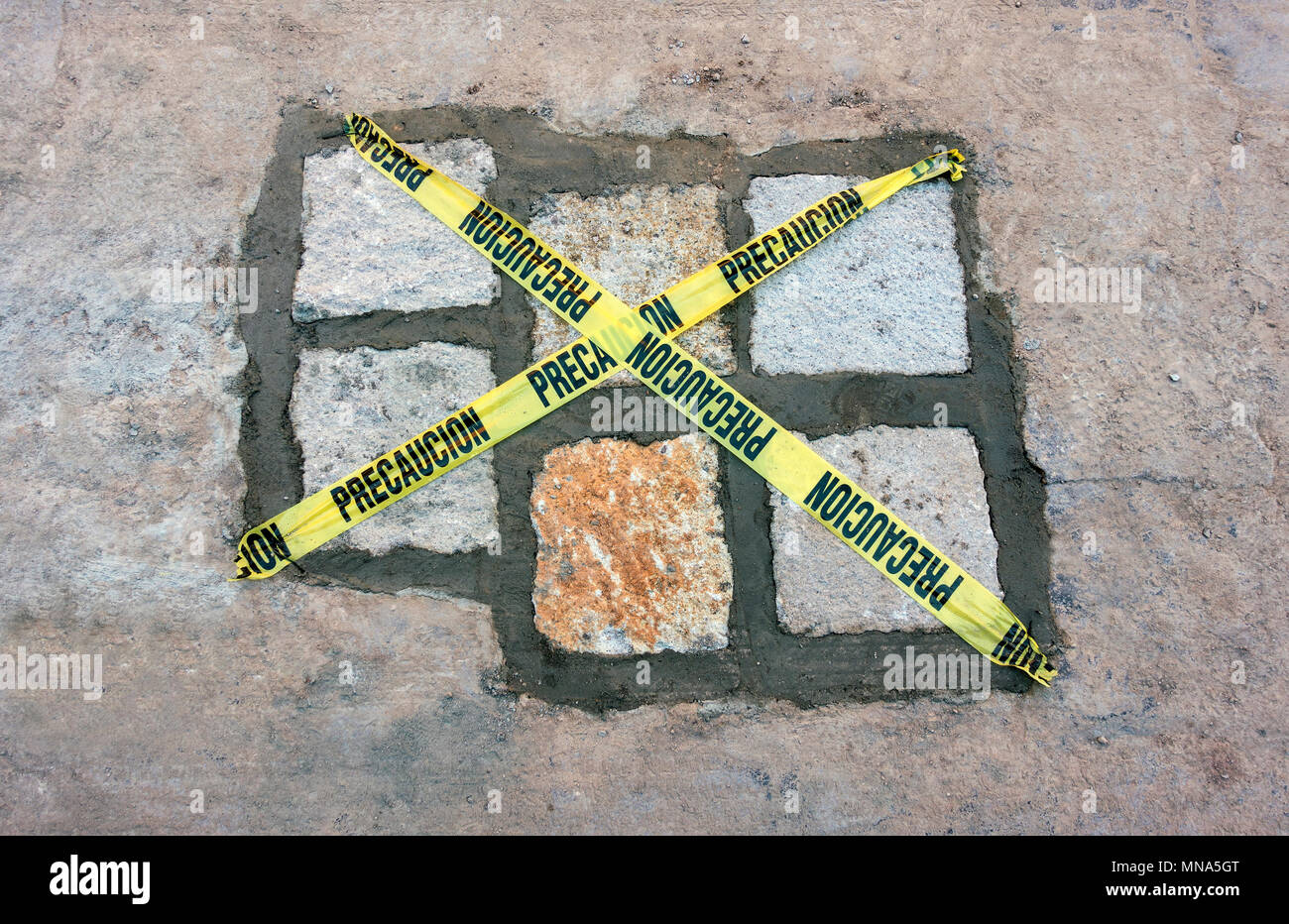 Replacement cobbles in a road in San Miguel de Allende, Mexico, with yellow warning strips Stock Photo