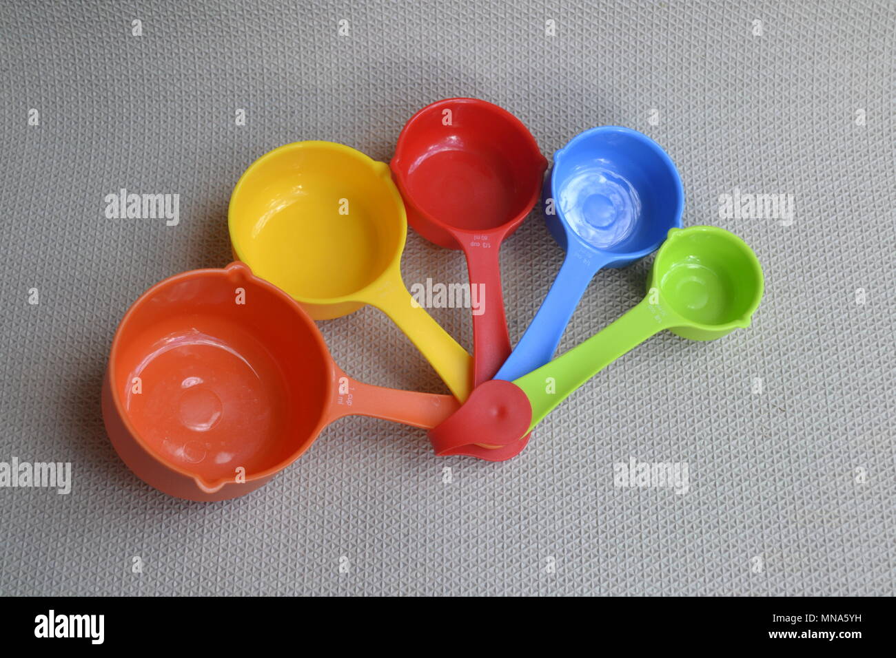 Nested Colorful rainbow kitchen measuring cups spoons colorful utensils Stock Photo