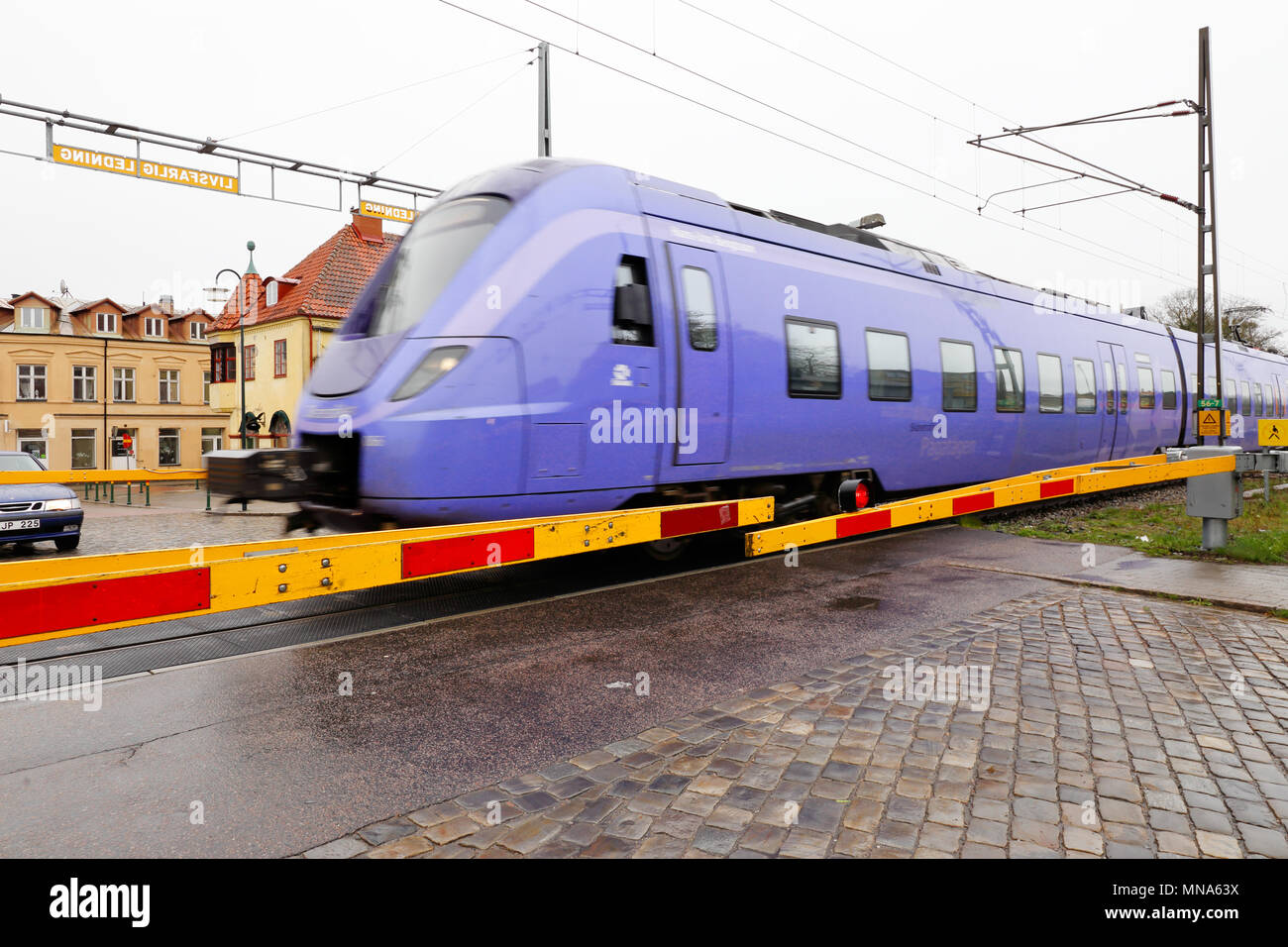 Tomelilla, Sweden - April 15, 2017: One blue class X61 commuter train passing a level crossing in the town Tomelilla. Stock Photo