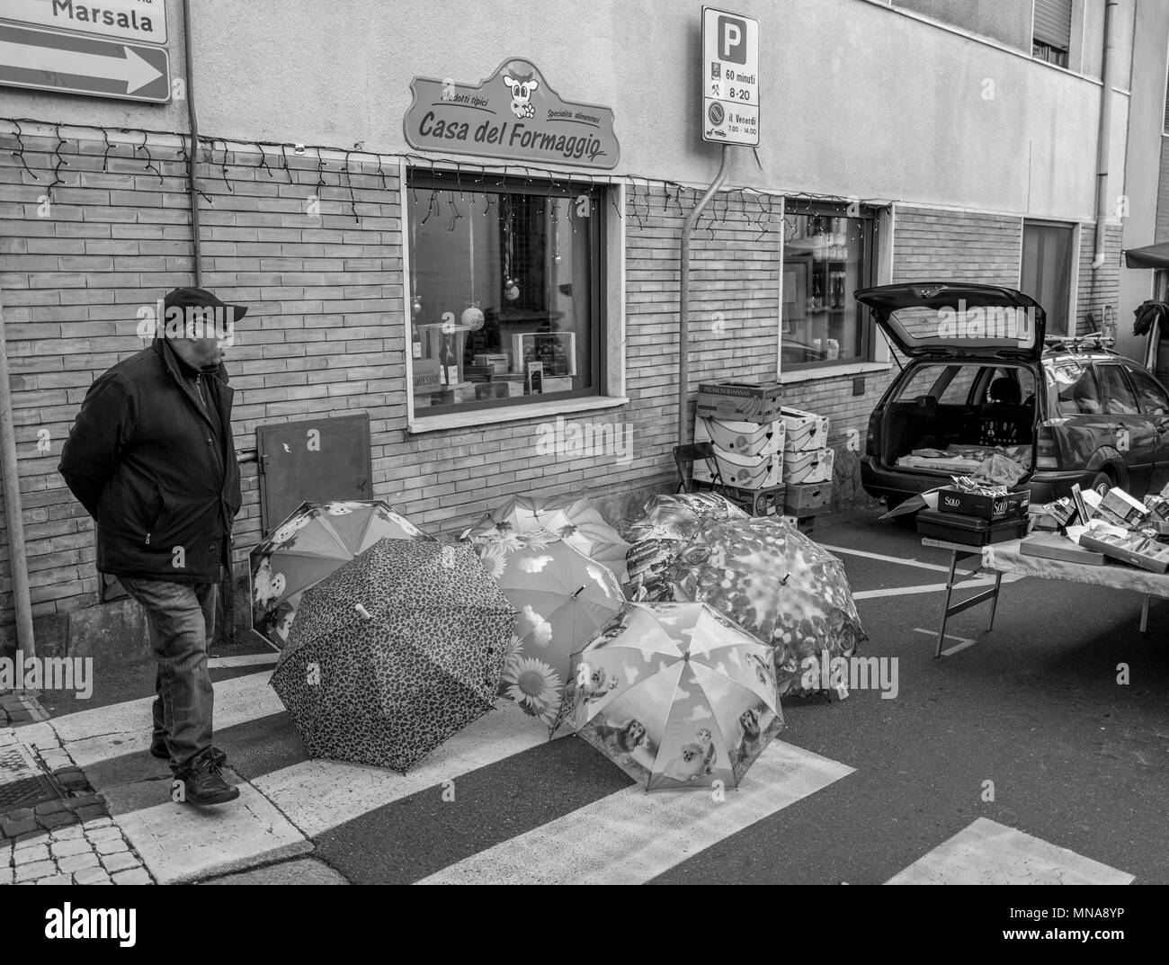 Gravirate, Lombardy, ITALY, View, Black&white, Saleman, selling, from the, back of a car, Umbrellas, displayed, in the street, for sale, at the, Friday Market,  Italy,  30/12/2016,     [© Peter SPURRIER], Stock Photo