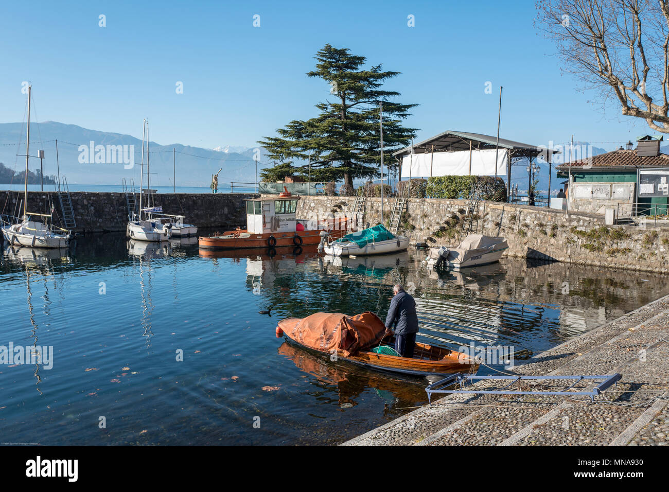View, of the, Stone built, enclosed Harbour, with a, fisherman, preparing, his, rowing boat.  Laveno, Province of Varese, Lombardy. ITALY.  31/12/2016  © Peter SPURRIER, Stock Photo