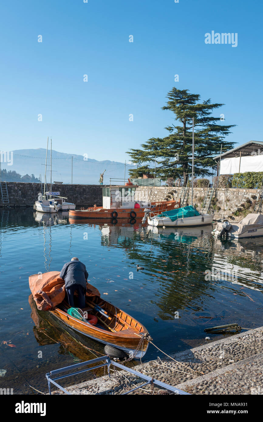 View, of the, Stone built, enclosed Harbour, with a, fisherman,  preparing, his, rowing boat.  Laveno, Province of Varese, Lombardy.  ITALY.  31/12/2016  © Peter SPURRIER, Stock Photo