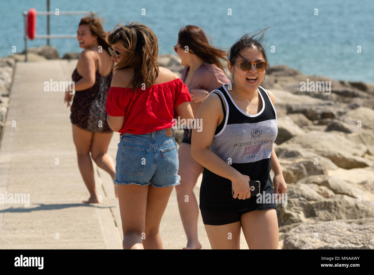 A group of teenage girls having fun choreographing their own dance routine on seafront rocks. Stock Photo