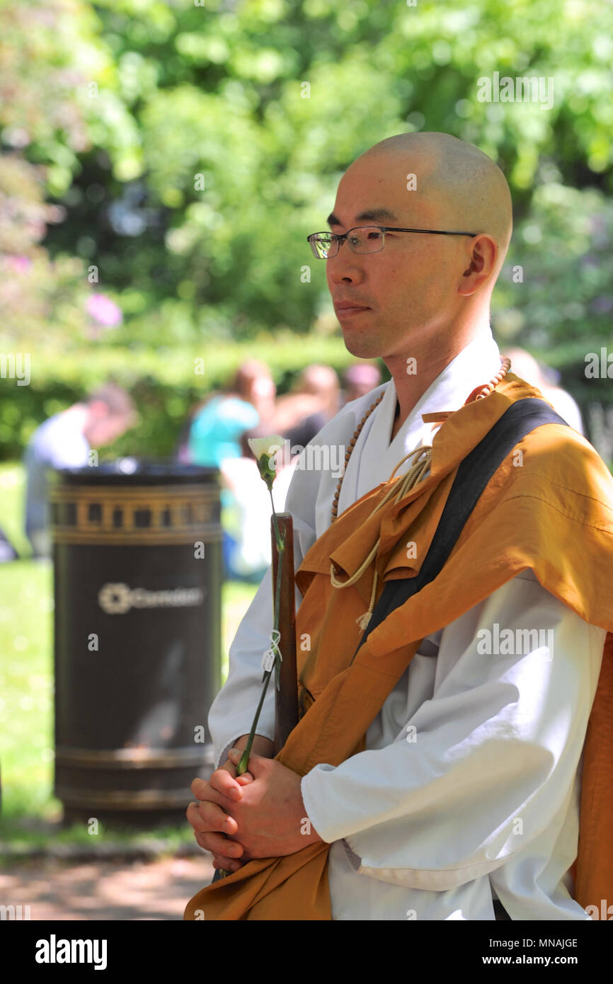 London, UK. 15th May 2018. A Buddhist monk holding a white carnation at the Conscientious Objectors Commemorative Stone, during a ceremony of remembrance held in Tavistock Square, London, UK to mark Conscientious Objectors Day.  79 white carnations were laid at the stone to commemorate various people who have historically refused to kill. Credit: Michael Preston/Alamy Live News Stock Photo