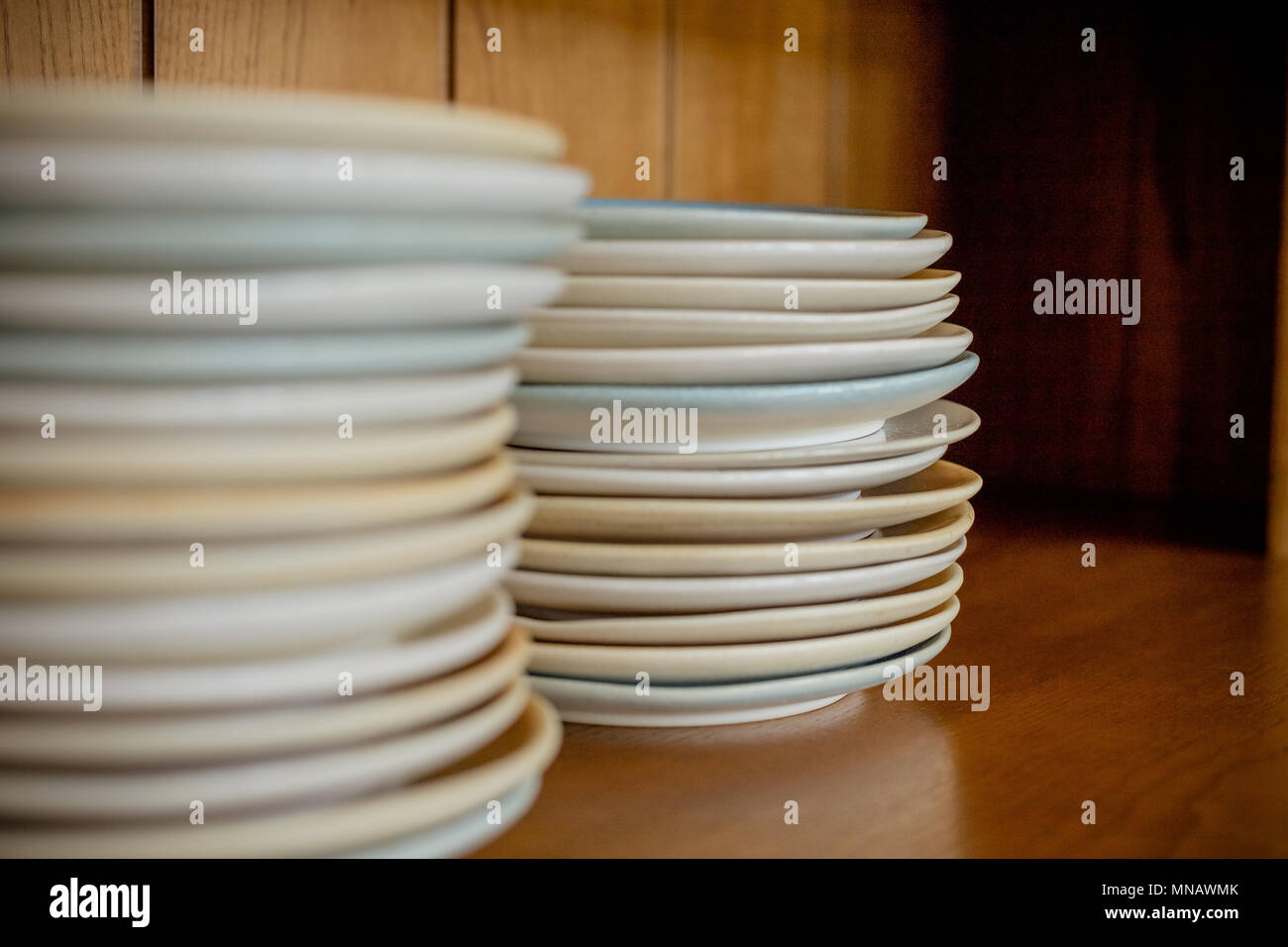 Group of white plates stacked together.Clean plates isolated on wooden shelf.Selective focus. Copy space Stock Photo