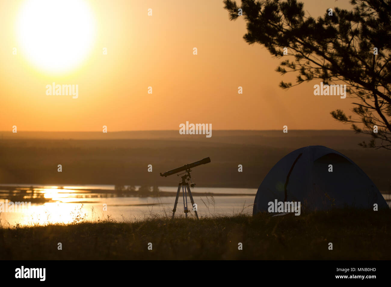 Tourist tent with telescope stands on the hill under the tree at ...