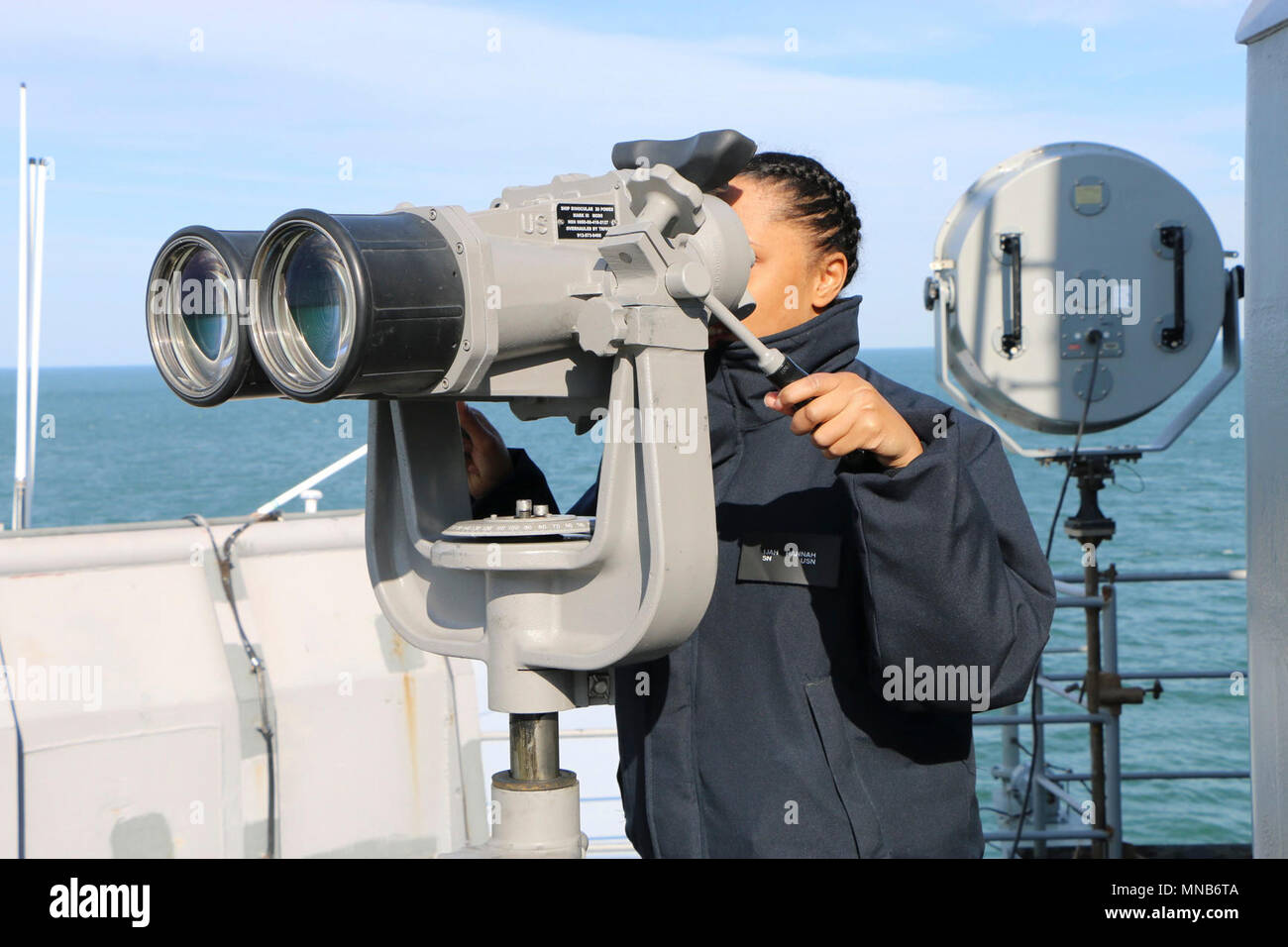ATLANTIC OCEAN (Mar. 15, 2018) Seaman Hannah Ijah scans the horizon for other ships while standing watch as the forward lookout aboard amphibious dock landing ship USS Gunston Hall (LSD 44).  Gunston Hall is underway participating in Carrier Strike Group FOUR Task Force Exercise in preparation for an upcoming deployment. (U.S. Navy Stock Photo