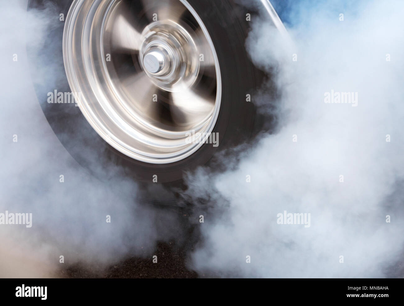 A car doing a burnout so that the tires spin smoke and smell of rubber