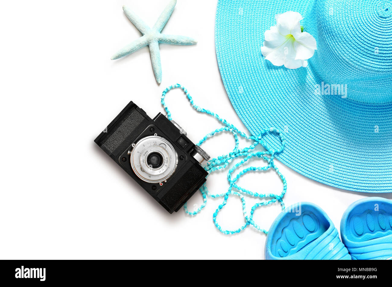 Vintage camera on white surface with beach items, top view. Stock Photo