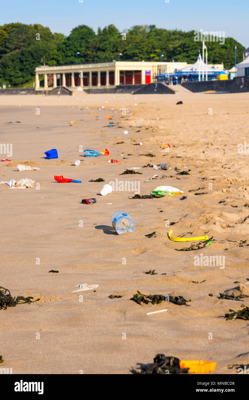 Foreground rubbish on the quiet sandy beach of Barry Island tourist resort early on a bright sunny summer morning. Stock Photo