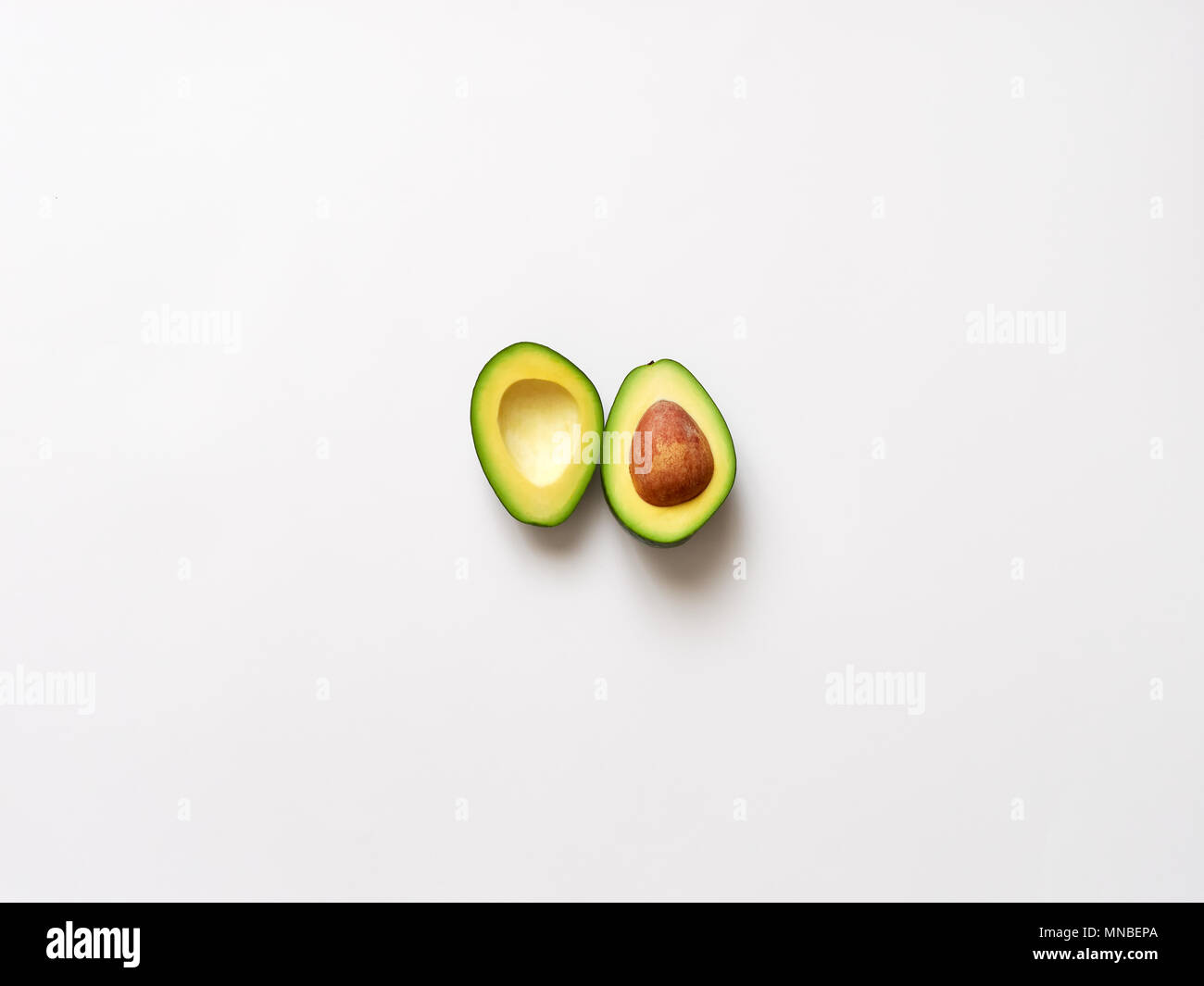 Avocado sliced with seed isolated in white background viewed from above - flatlay look Stock Photo